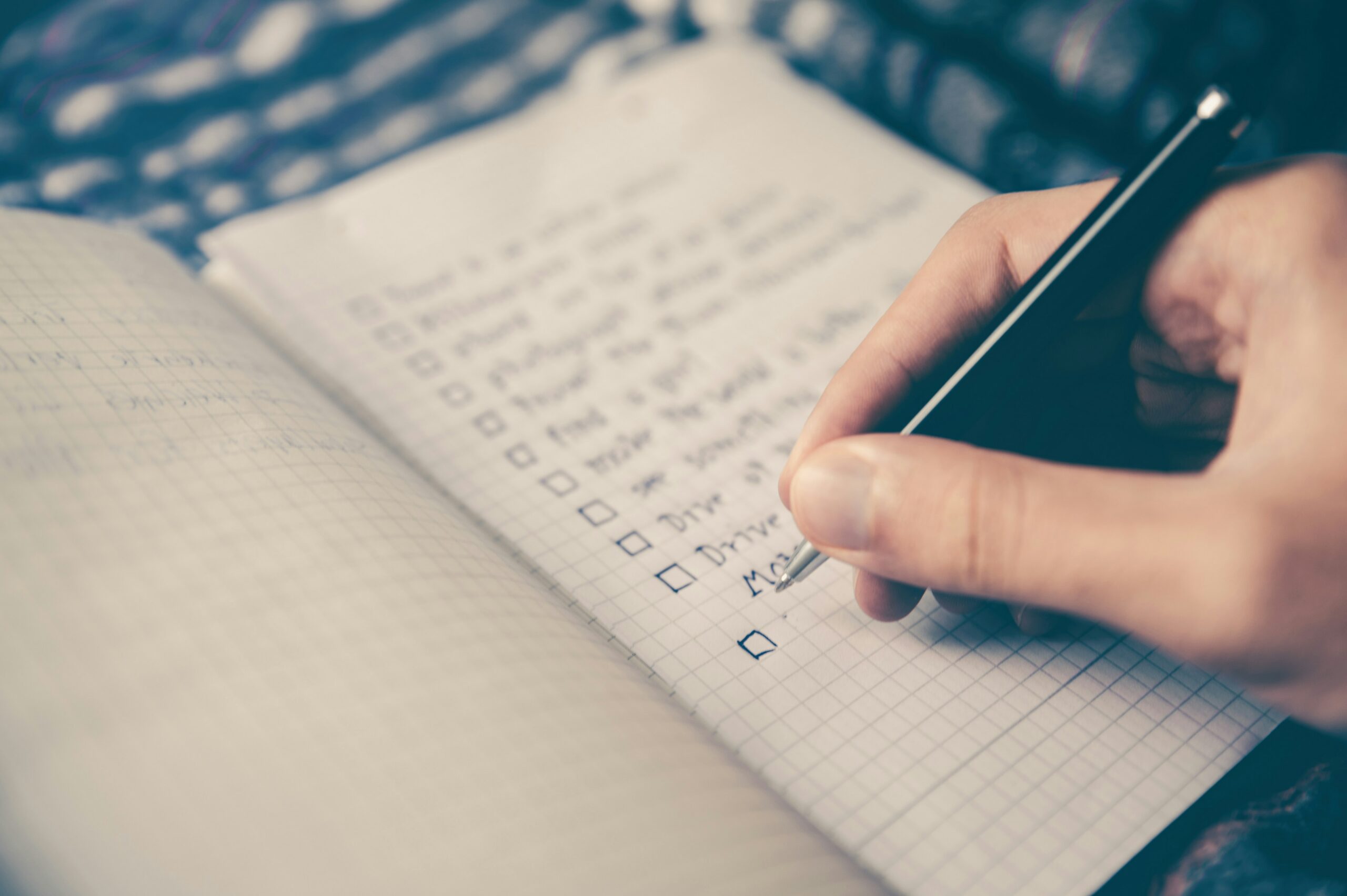 an image of a notebook with a checklist drawn on it. a hand holding a pen is checking items off.